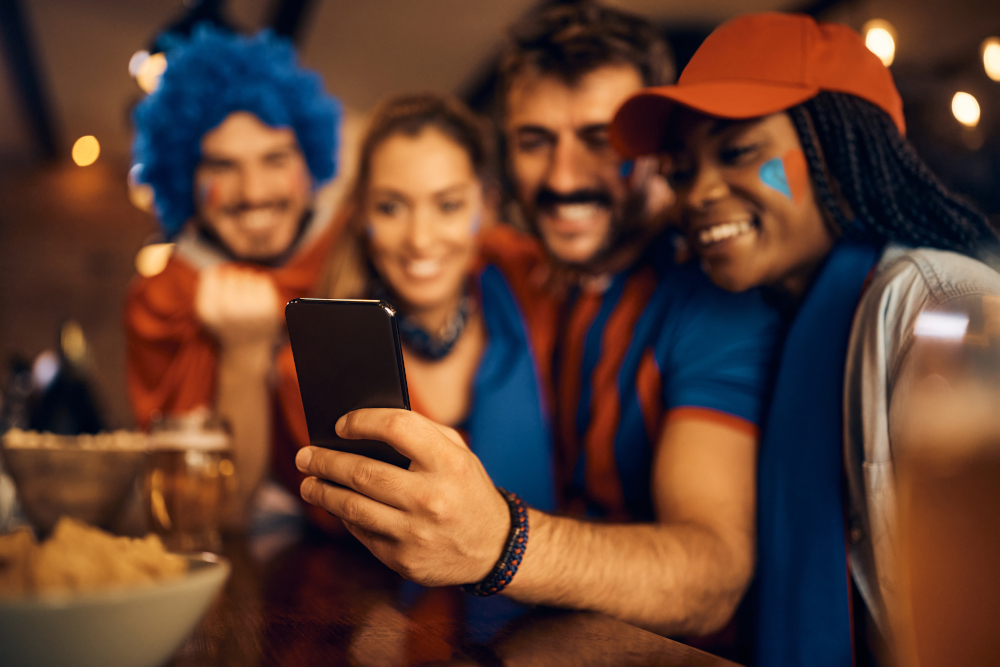 Close up of soccer fans watching a game on smart phone in pub.